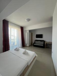 a bedroom with a large white bed and a television at Christale Rooms in Năvodari