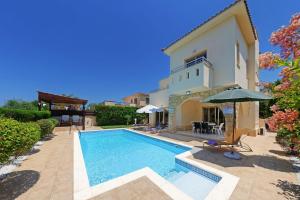 einen Pool vor einem Haus mit Sonnenschirm in der Unterkunft Luxury Coral Bay Villa Villa Shanta 3 Bedroom Villa Distant Sea Views in Peyia