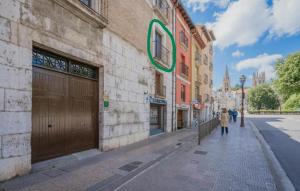 a woman walking down a street next to a building at Centro Burgos Real Consulado 1787 in Burgos