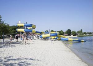 a group of people on a beach with a water slide at Vakantiepark Klein Strand - Luxe Chalet 6p in Jabbeke