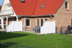 a house with a red roof with two white fences at Ferienhaus Skanhuus in Klütz