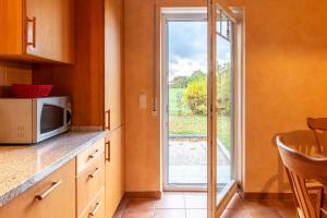 eine Küche mit einer Mikrowelle und einer Glasschiebetür in der Unterkunft Ferienhaus Strandmuschel in Groß Schwansee