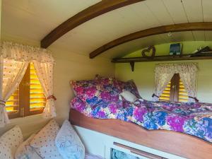 a bed in a small room with two windows at Yule Tree Campsite in Helston