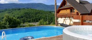 a swimming pool in front of a house with a mountain at Gazdówka na Mosornym Groniu in Zawoja
