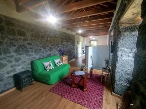 a living room with a green couch and a table at Bragada Stonehouse in São Roque do Pico