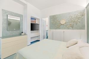 a white bedroom with a bed and a tv at Villa Ambra 10, Emma Villas in Sorso