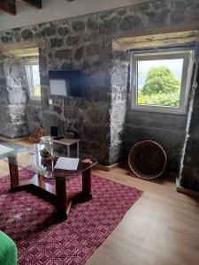 a living room with a table and a window at Bragada Stonehouse in São Roque do Pico