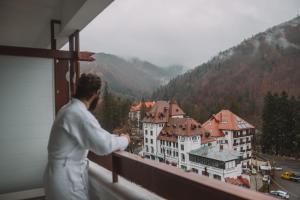 a man standing on a balcony looking at a city at Hotel Sinaia in Sinaia +45 photos