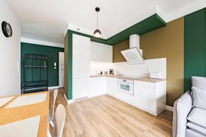 a kitchen with white cabinets and green walls at Comfort Apartments Batorego in Gdynia