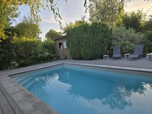 a swimming pool with two chairs and a house at Il était une fois in Herbeumont