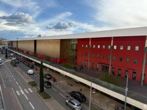 a large red building with cars parked in a parking lot at Face à la gare - Chambre 6 in Roanne