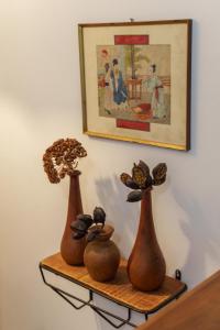 three vases sitting on a shelf under a painting at Casa Alderotti in Bologna +28 photos