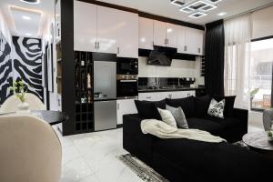 a living room with a black couch and a kitchen at Brand New 2bed flat close to the beach with 2 balconies in Lekki