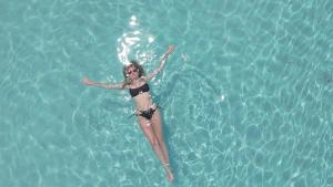 a woman swimming in a pool of water at Madi Maldives Ukulhas in Ukulhas