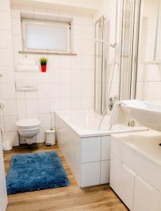 a bathroom with a tub and a sink and a toilet at janu-homes - 2 Zimmer Apartment - 4 Betten, Lahnblick vom Amselweg in Runkel +8 photos