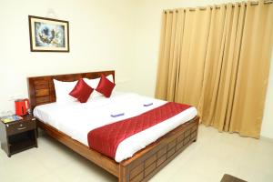 a bedroom with a large bed with red pillows at Shastik Residency in Oragadam +12 photos