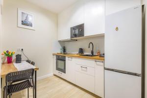 a kitchen with white cabinets and a table and a refrigerator at Miedza Apartament - Targówek, Metro Trocka in Warsaw