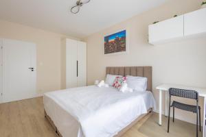 a white bedroom with a bed and a desk at Miedza Apartament - Targówek, Metro Trocka in Warsaw