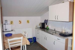 a kitchen with white cabinets and a table and a sink at One-Bedroom Apartment in Putbus II in Putbus