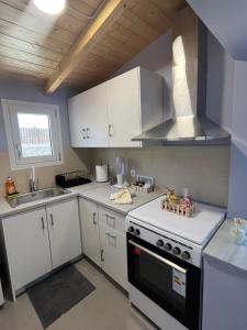a kitchen with white cabinets and a stove top oven at Nick House Nikiana in Nikiana +18 photos