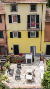 ein gelbes Haus mit Stühlen und Tischen in einem Innenhof in der Unterkunft Alba apartments in Biassa