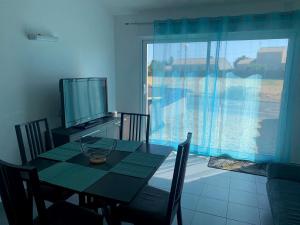 a dining room with a table and a television at La Grisot de la mer Saint Hilaire in Saint-Hilaire-de-Riez