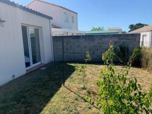 a backyard with a brick wall and a fence at La Grisot de la mer Saint Hilaire in Saint-Hilaire-de-Riez