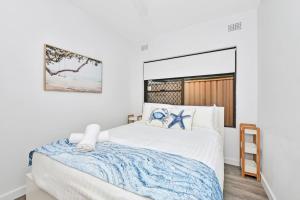 Un dormitorio con una gran cama blanca con una manta azul. en Waterfront Reflections, en Corlette