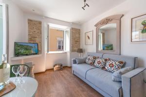 a living room with a blue couch and two windows at Tobacco House Suites in Corfu