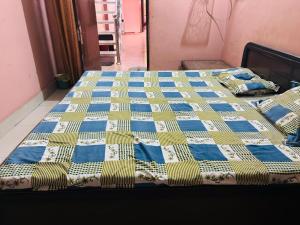 a bed with a blue and yellow quilt on it at Ram ji guest house in Parwanoo