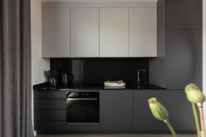 a kitchen with white cabinets and a black oven at Scala Apartamenty by Moderna Profit- Łąkowa 60E in Gdańsk