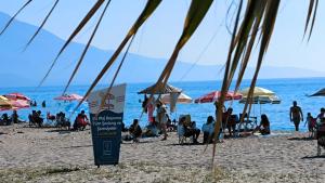 people on a beach with umbrellas and the ocean at Villa Plaj in Kusadası