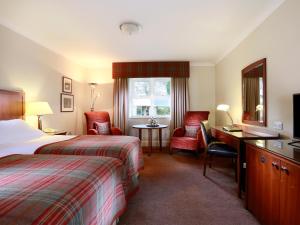 a hotel room with two beds and a table at Macdonald Portal Hotel, Golf & Spa Cobblers Cross, Cheshire in Tarporley