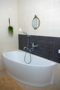 a white bath tub in a bathroom with a mirror at Hotel Centras in Šakiai