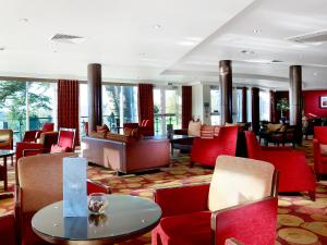 a hotel lobby with red chairs and a table at Macdonald Portal Hotel, Golf & Spa Cobblers Cross, Cheshire in Tarporley