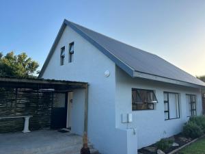 a white house with a garage and a building at Lavender Cottage in Cape St Francis