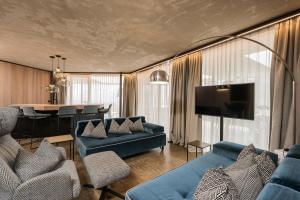 a living room with a blue couch and a dining room at Lindenhof Pure Luxury & Spa DolceVita Resort in Naturno