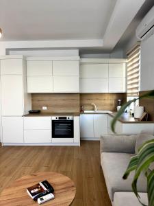 a kitchen and living room with white cabinets and a table at Apartment's Aquilo Blloku in Tirana