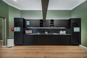 a kitchen with black cabinets and a sink at HOME1 - Douzième Boutique Hostel in Vienna