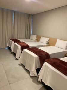 three beds are lined up in a room at Hotel Haven Guarulhos in Guarulhos