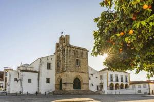 an old stone building with a tower on a street at Simply House in Faro