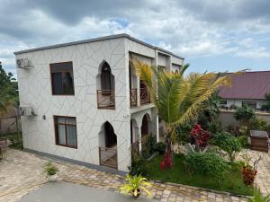 a white building with a palm tree in front of it at Boutique View Garden Kendwa in Kendwa +4 photos