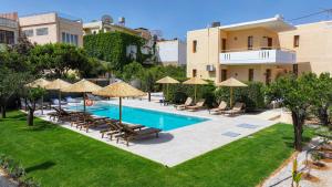 a pool with chairs and umbrellas next to a building at Kydonia apartments in Platanias