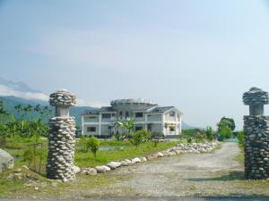 a road with two stone pillars in front of a house at 167 Original Farm B&B in Xikou
