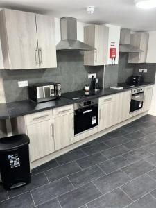 a kitchen with wooden cabinets and a black counter top at Cosy Double Room in Professional Unique Complex in London +3 photos