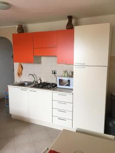 une cuisine avec des armoires rouges et un réfrigérateur blanc dans l'établissement Castelsardo Romantica, à Castelsardo