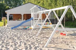 un parco giochi con altalena incastonata nella sabbia di PLAŻOWICZE - domki letniskowe dla rodzin z dziećmi a Mielno