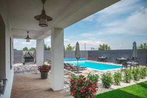 a patio with a swimming pool with a table and umbrellas at Palkonyha Panzió Speiz Gasztroműhely in Palkonya