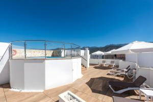 a balcony with chairs and umbrellas on a building at Hotel Toboso Chaparil in Nerja