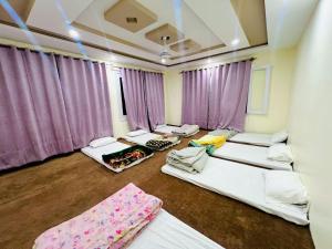 a room with four beds in it with purple curtains at Zim Zim &Salaar Gust House in Skardu